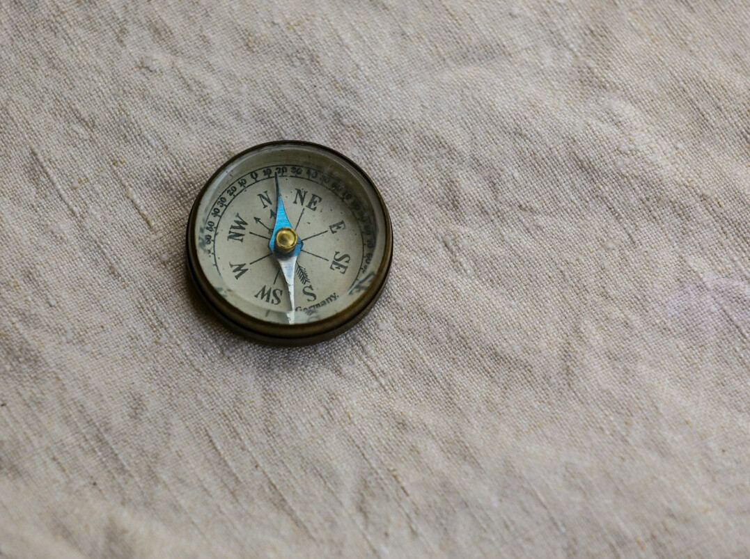 Weathered old map of a coastal region with a brass compass on top