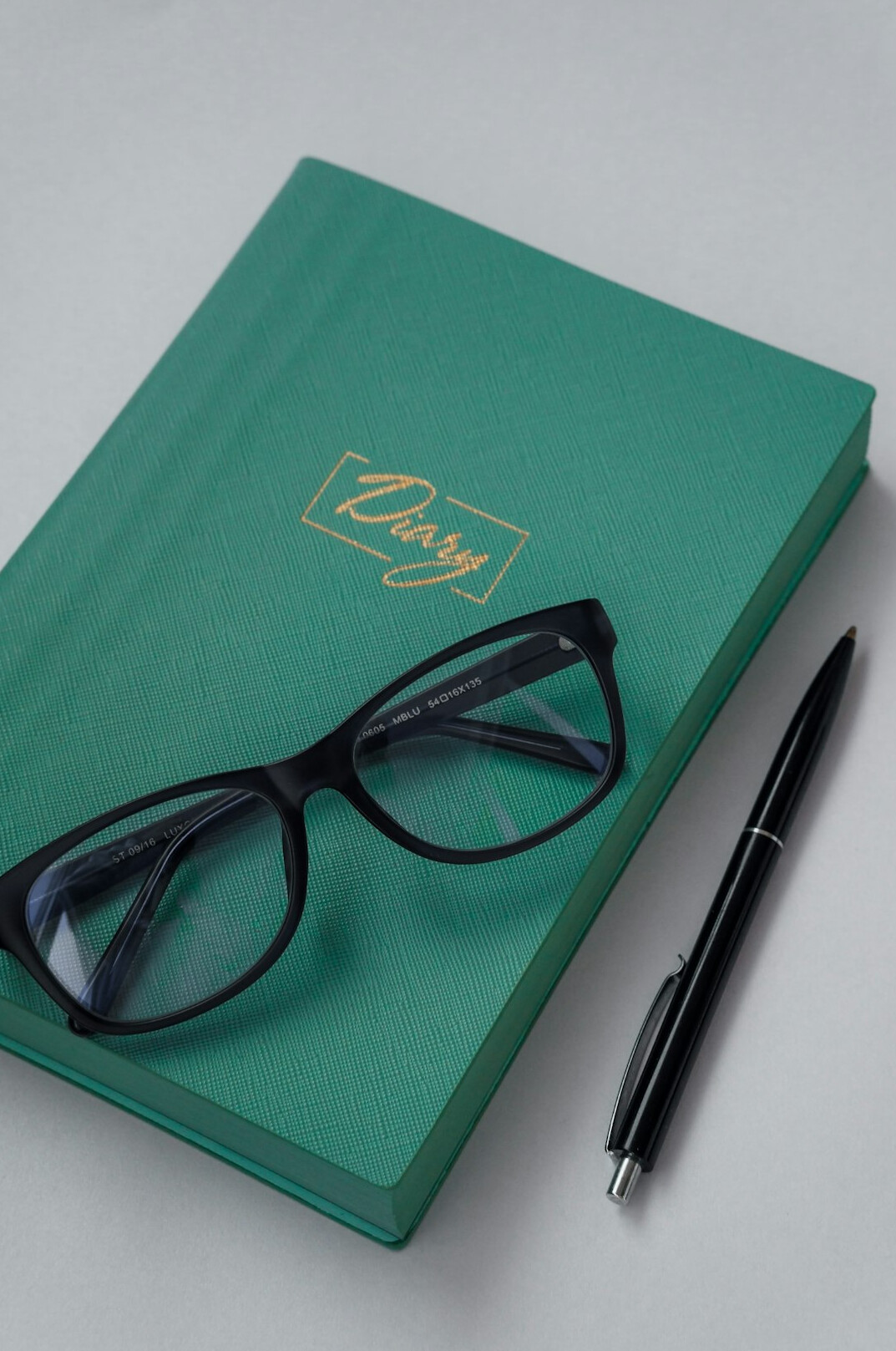 Open notebook with handwritten notes, a fountain pen and reading glasses on a desk
